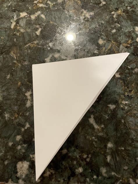 Fold the paper in half diagonally to form a triangle.