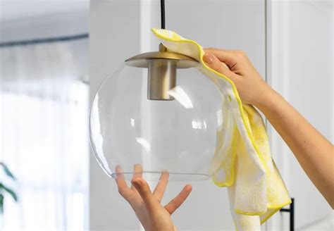 Person looking at a ceiling light and choosing a simple cleaning method with cloth and bowl nearby